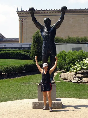 Andrea Hoare en la estatua de Rocky Balboa junto a las escaleras del Museo de Arte de Filadelfia. Guía para visitar Filadelfia desde Nueva York - Foto de AHM