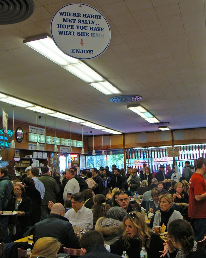 Gente comiendo al Interior de Katz Deli en el Lower East Side de Manhattan. En el techo cuelga el letrero que indica donde Sally conoció a Harry. Foto de AHM