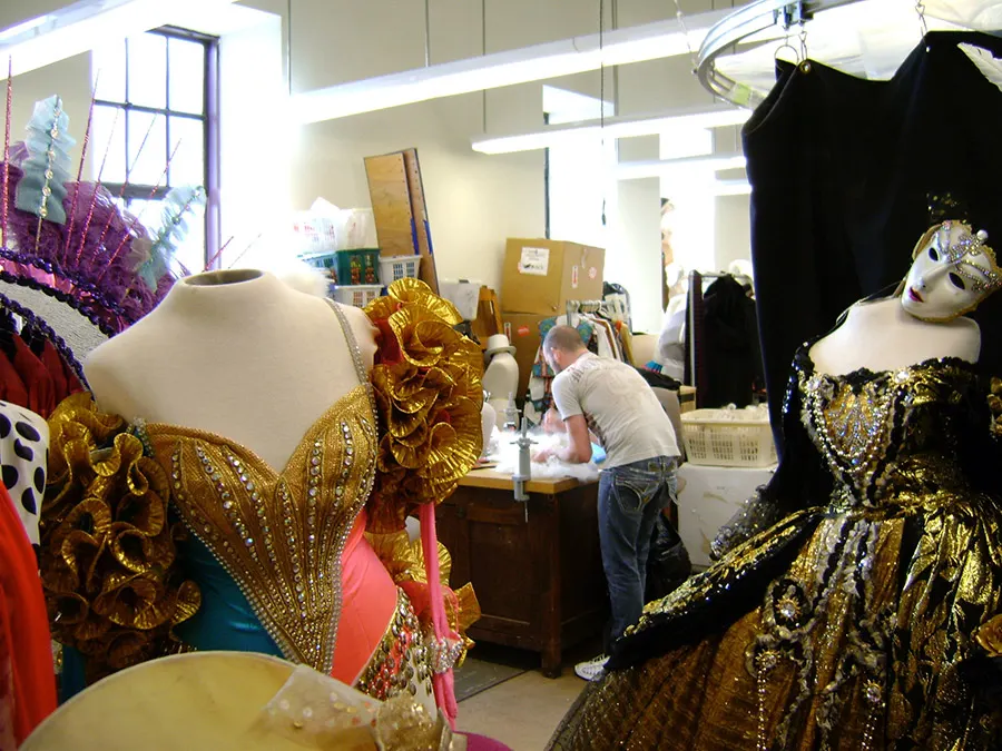 Interior del taller de costura donde hacen el vestuario para los shows del Radio City Music Hall, se ve disfraces listos y a un diseñador trabajando - Foto de Andrea Hoare Madrid