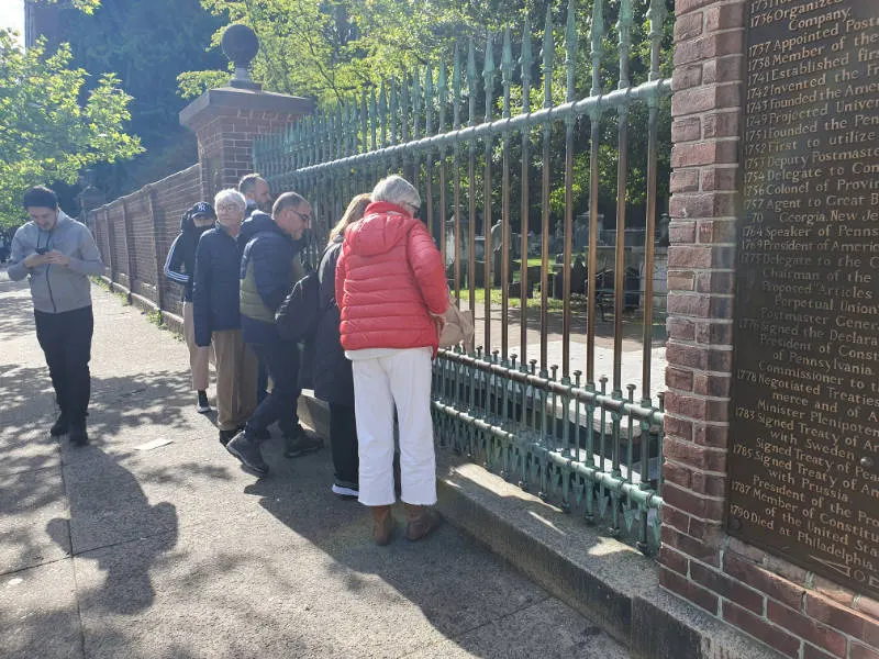 Visitantes tirando monedas a la Tumba de Benjamin Franklin en el Christ Church Burial Ground. Foto de Andrea Hoare Madrid