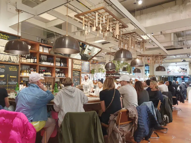 People eating at the counter of one of the stalls at the EATALY Italian food market in Manhattan's Flatiron District. Photo by Andrea Hoare Madrid
