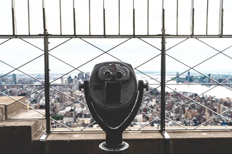 Telescopio y rejas del mnirador del piso 86 del Empire State Building. Foto de Eri J en Unsplash, Licencia Unsplash. Disponible en https://unsplash.com/es/fotos/un-parquimetro-que-funciona-con-monedas-en-la-parte-superior-de-un-edificio-r9TA1cnKC20