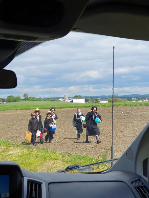 Mamá y niños de la comunidad Amish de Lancaster en Pensilvania, caminando por el campo a su casa al terminar el colegio. Foto de Andrea Hoare Madrid desde el interior de un auto durante una excursión de Nueva York a Filadelfia y el Amish Country