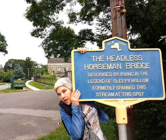 Andrea Hoare detrás del letrero en Sleepy Hollow que indica donde estaba el puente del Jinete sin Cabeza descrito por Washington Irving en su relato La Leyenda de Sleepy Hollow. Foto de Marina Madrid
