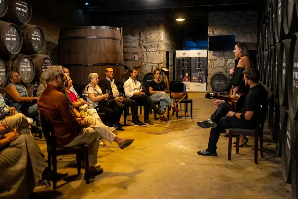 Audience seated among port wine barrels watching a Fado show at Quinta da Boeira