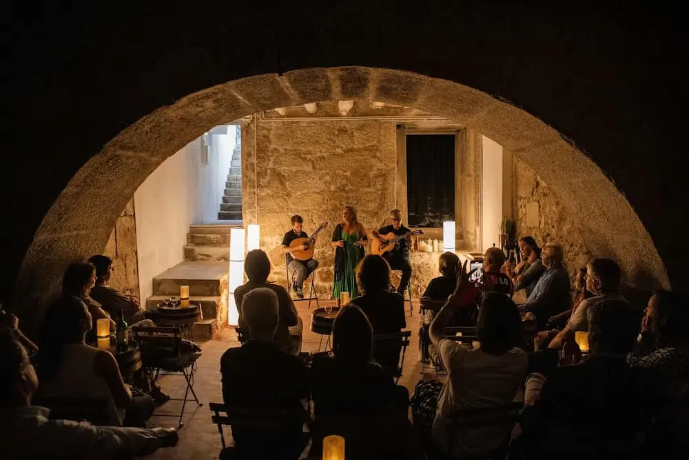 Fado concert under a stone arch at A Casa do Fado in São João Novo, Porto