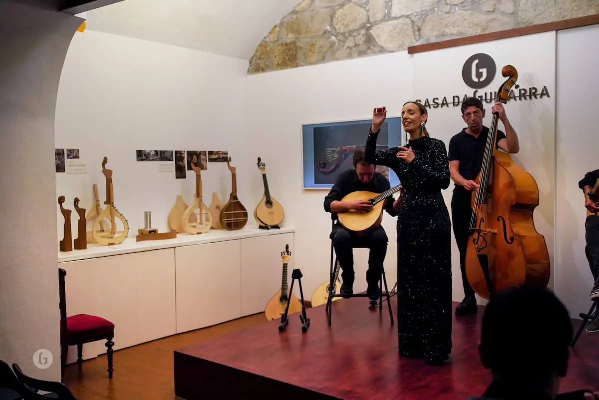 Fado singer with guitar and double bass players on stage at Casa da Guitarra in Porto