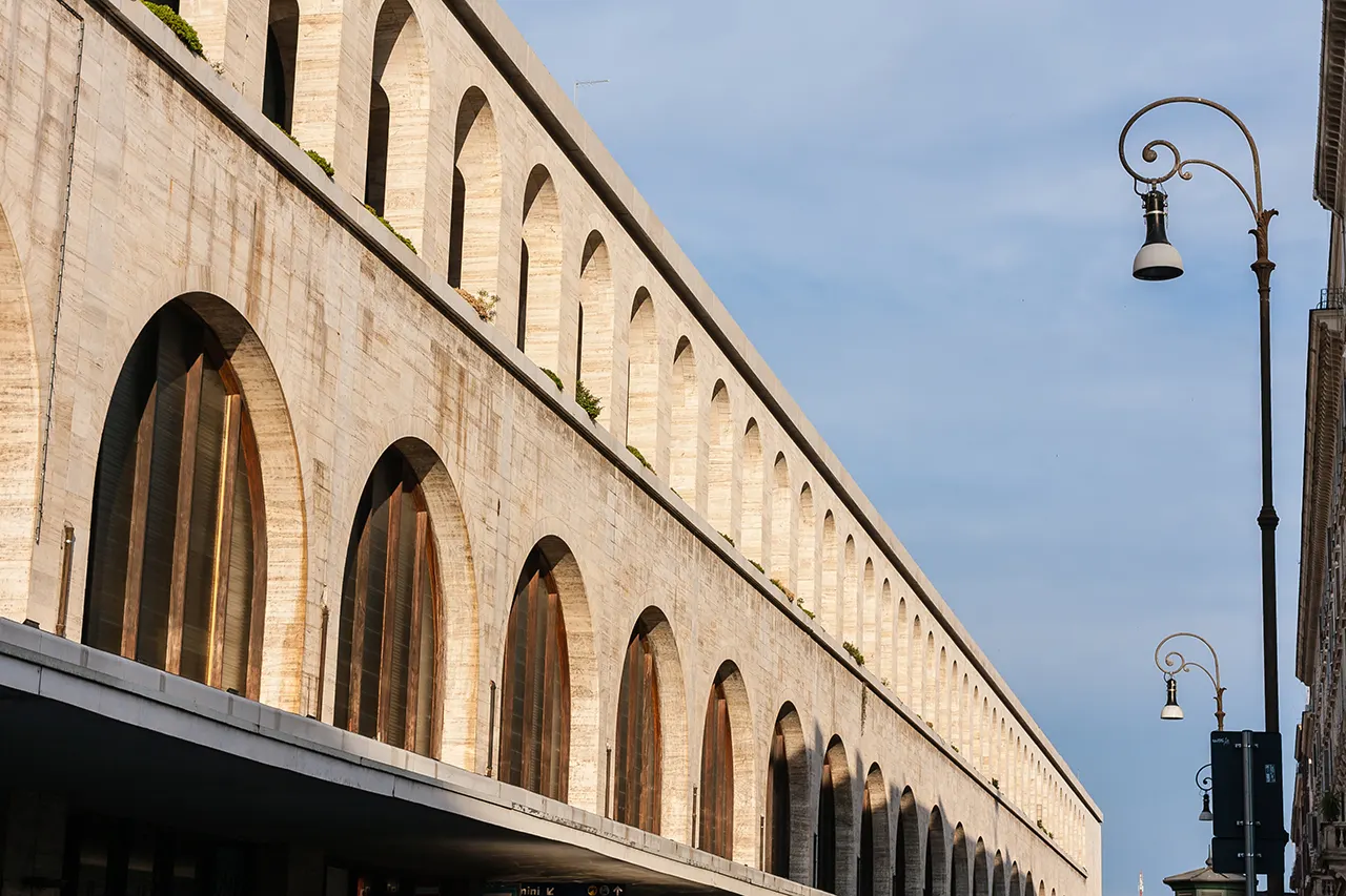 Fachada exterior de la Estación Termini con arcos y farola en Roma.