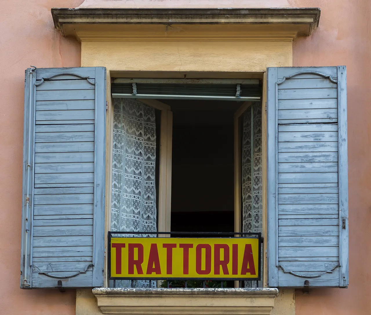 Ventana de trattoria italiana con persianas azules.