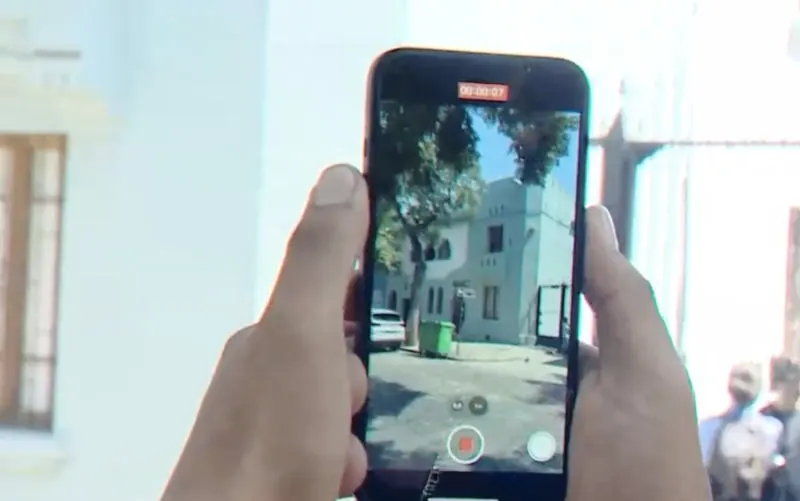 Mano y celular de una persona sacando una foto a la residencia presidencial de Gabriel Boric en Santiago. Captura de pantalla de un video disponible en https://www.cnnchile.com/pais/casa-gabriel-boric-barrio-yungay_20220215/
