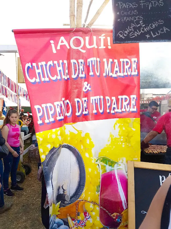 Letrero de un local de una fonda de la Semana de la Chilenidad que dice: "aquí chicha de tu madre y pipeño de tu padre". Foto de AHM