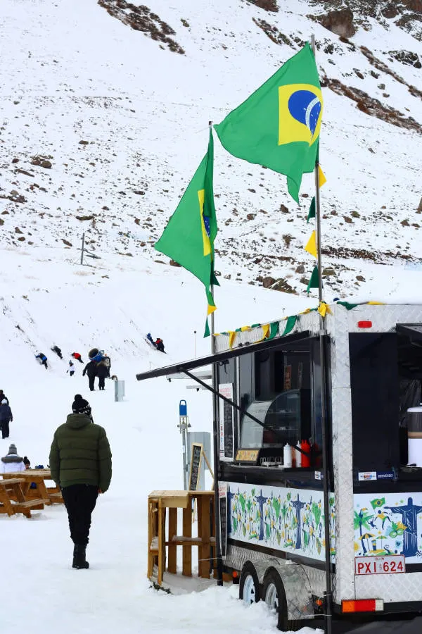 Food Car en Farellones con banderas brasileñas. Foto de Nathana Rebouças en Unsplash. Disponible en https://unsplash.com/es/fotos/hombre-en-chaqueta-marron-de-pie-en-el-suelo-cubierto-de-nieve-durante-el-dia-P8qYOu3SOG0