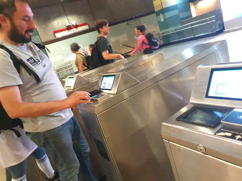Persona escaneando el código QR desde su celular en el torniquete de la estación Los Dominicos del Metro de Santiago. Foto de Andrea Hoare Madrid